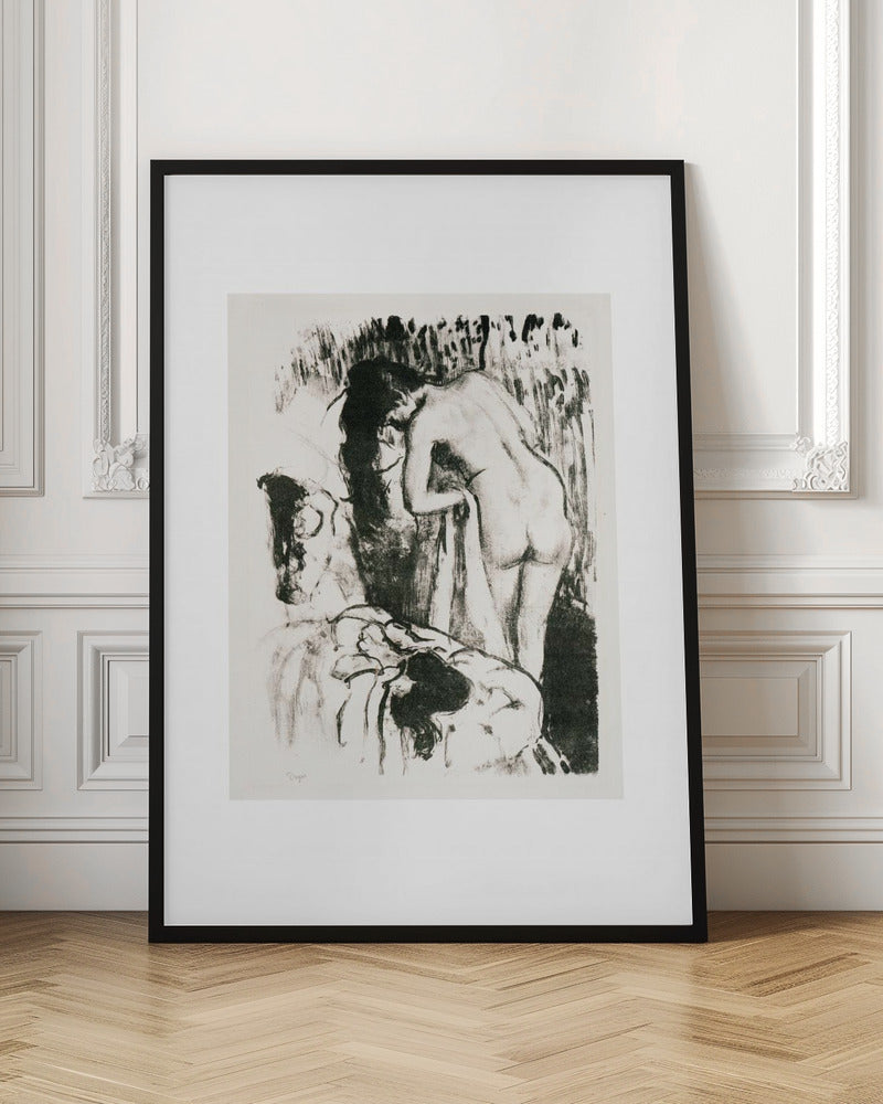 A framed black and white lithograph by Edgar Degas of a nude woman with long dark hair, viewed from the back as she leans over. The artwork has a sketchy, impressionistic style, capturing an intimate moment. Wall Art