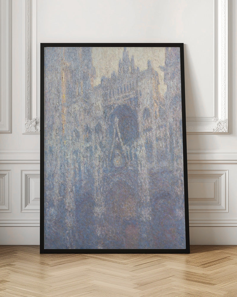 An Impressionist painting by Claude Monet depicting the Rouen Cathedral. The view is a close-up of the facade, rendered in hazy, textured brushstrokes with a predominantly blue, gray, and pale yellow color palette, suggesting early morning light or fog. The painting is enclosed in a simple black frame. Artwork
