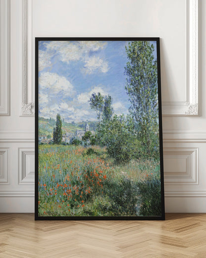 An impressionist painting depicting a vibrant green field filled with red poppies under a bright blue sky with fluffy white clouds. Tall green trees stand on the right, and in the distance, a small village with a church steeple is nestled in the rolling hills. Decor