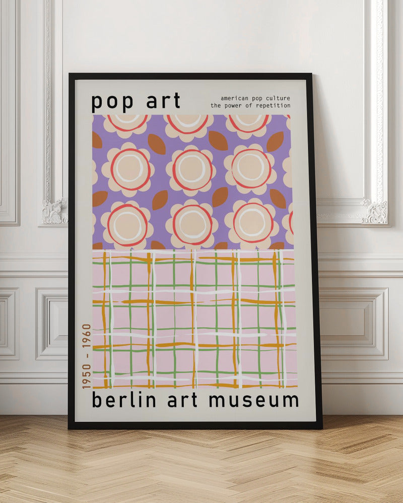 A framed pop art museum poster advertising an exhibition at the Berlin Art Museum. The poster features two distinct patterns. The top section has repeating stylized cream and red flowers on a purple background, with the words 'pop art' and 'american pop culture the power of repetition'. The bottom section displays a pink, green, and orange plaid pattern. The dates '1950 - 1960' are printed vertically on the side. Artwork