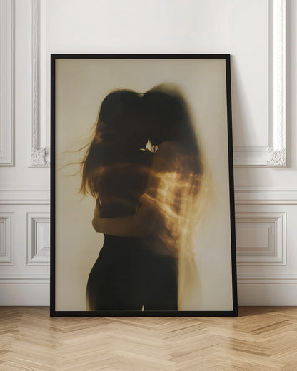 An artistic, long-exposure photograph of two silhouetted figures embracing. Their forms are blurred with motion, and streaks of warm, golden light wash over them against a soft, off-white background, creating a dreamy and intimate mood. Decor