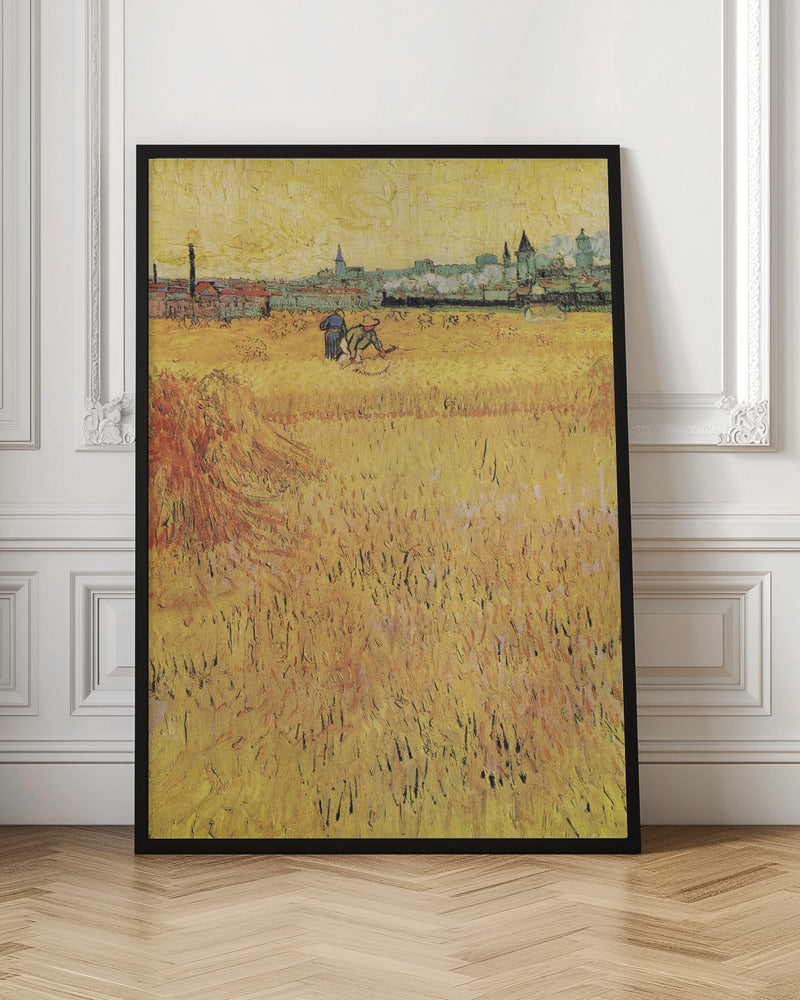 A Post-Impressionist painting by Vincent van Gogh depicting a vast, golden wheat field under a yellow sky. Two figures are harvesting wheat in the middle distance, with a town and industrial buildings on the horizon. The artwork is characterized by thick, textured brushstrokes and is displayed in a black frame. Print