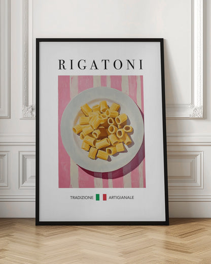 A framed art print of a vintage-style Italian food poster. It features a painting of a white plate full of uncooked rigatoni pasta on a pink and white striped background. The word 'RIGATONI' is printed in large black letters at the top, and 'TRADIZIONE ARTIGIANALE' with a small Italian flag is printed at the bottom. Artwork