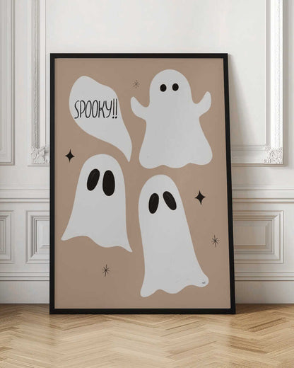 A playful illustration for Halloween featuring three cute, cartoonish white ghosts with black eyes against a solid light brown background. One ghost is accompanied by a speech bubble that reads 'SPOOKY!!' in a hand-drawn font. Small black stars and asterisks are scattered around the ghosts. The artwork is enclosed in a thin black frame. Decor
