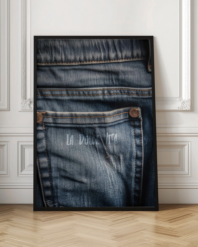 A detailed close-up photograph of a faded blue jean back pocket, showing the texture of the denim, orange stitching, and a copper rivet. Faint white text is stenciled onto the pocket. Poster