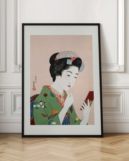 A Japanese ukiyo-e woodblock print of a woman in a green kimono applying red lipstick while looking into a small handheld mirror. Her black hair is elaborately styled, and the background is a soft pink. Artwork