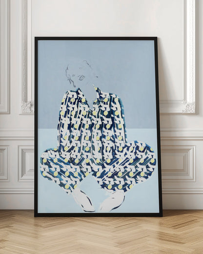 A framed fashion illustration of a person sitting cross-legged against a light blue background. The figure wears a bold, patterned blue, white, and yellow outfit, while their face and hair are rendered as faint, delicate line drawings. Wall Art
