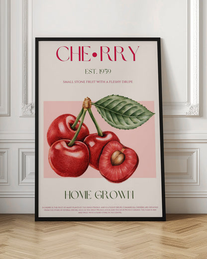 A vintage-style botanical poster of cherries with a black frame. The poster features a detailed illustration of four red cherries on a pink background. Above the illustration, the word 'CHERRY' is printed in large magenta letters, with 'EST. 1959' below it. At the bottom, it says 'HOME GROWN' in green, followed by a descriptive paragraph about cherries on a cream background. Poster