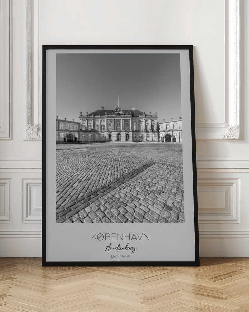 A framed, vertical black and white photograph of Amalienborg Palace in Copenhagen. The shot is taken from a low angle, emphasizing the large cobblestone square in the foreground. The palace stands symmetrically in the background under a clear sky. At the bottom of the poster, text reads 'KØBENHAVN', 'Amalienborg', and 'DANMARK'. Poster
