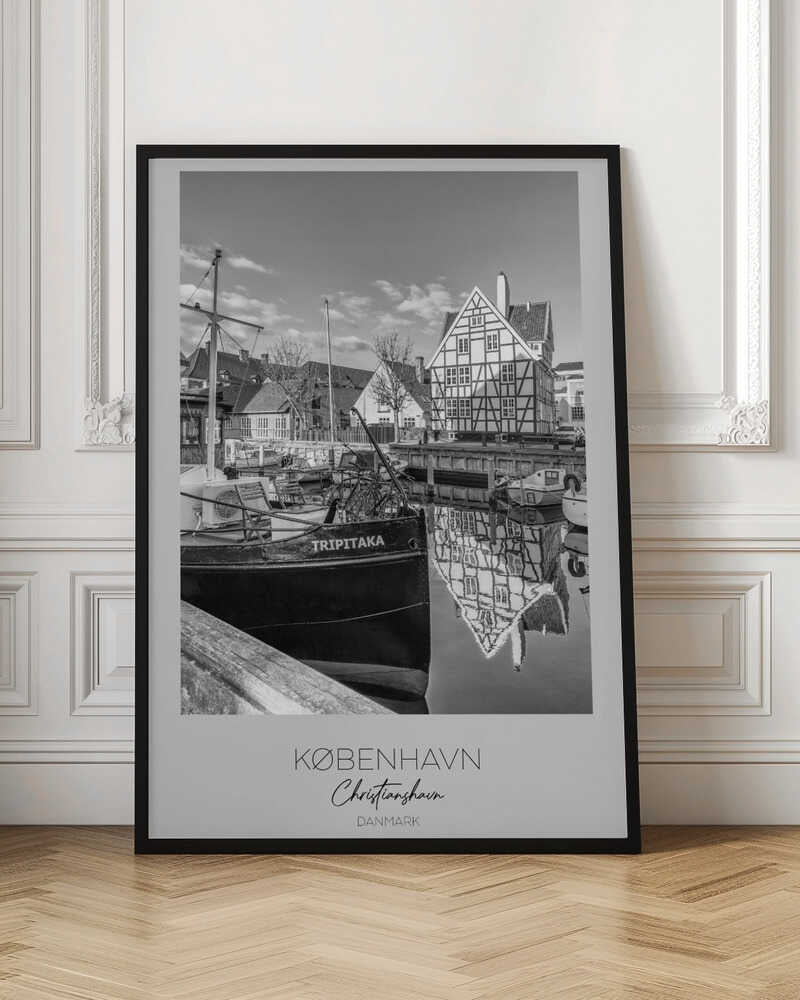 A black and white travel poster featuring a photo of Christianshavn in Copenhagen. The scene shows a boat named 'TRIPITAKA' docked in a canal, with a prominent half-timbered building across the water, its reflection visible on the surface. The bottom of the poster has text that reads 'KØBENHAVN', 'Christianshavn', and 'DANMARK'. Artwork