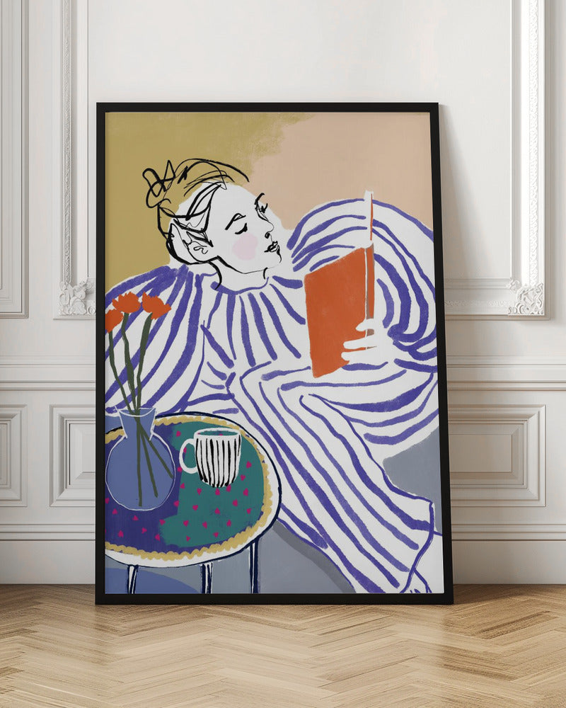 A stylized, framed illustration of a person with dark hair in a messy bun, wearing a blue and white striped top, reclining comfortably while engrossed in an orange book. Beside them is a small table with a blue vase holding three orange flowers and a black and white striped mug. The background is a soft beige color. Print