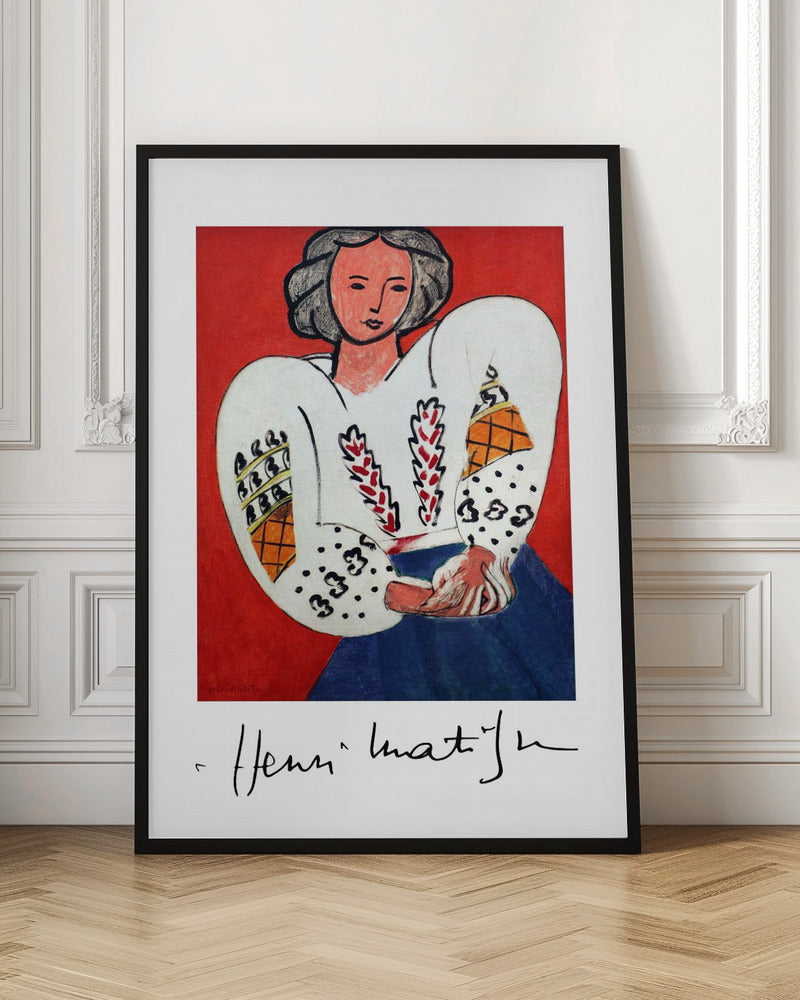 A framed art print of Henri Matisse's 'La Blouse Roumaine' (The Romanian Blouse). The painting depicts a woman with dark, styled hair against a vibrant solid red background. She is wearing a voluminous white blouse with puffy, intricately decorated sleeves and a dark blue skirt. Her hands are clasped in front of her. Below the image is the signature 'Henri Matisse'. Wall Art