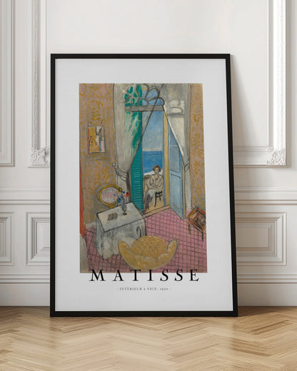 A poster of Henri Matisse's 1920 painting 'Intérieur à Nice'. The artwork depicts a room interior with an open door leading to a balcony where a woman sits overlooking the sea. The poster is in a black frame with 'MATISSE' written at the bottom. Print