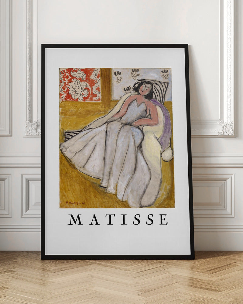 An art print poster of a Henri Matisse painting. The image features a woman with dark hair wearing a long, light-colored dress, reclining in a golden-yellow armchair. The background includes a red and white floral pattern and other decorative elements. The word 'MATISSE' is printed in large black letters below the artwork, all enclosed in a black frame. Decor