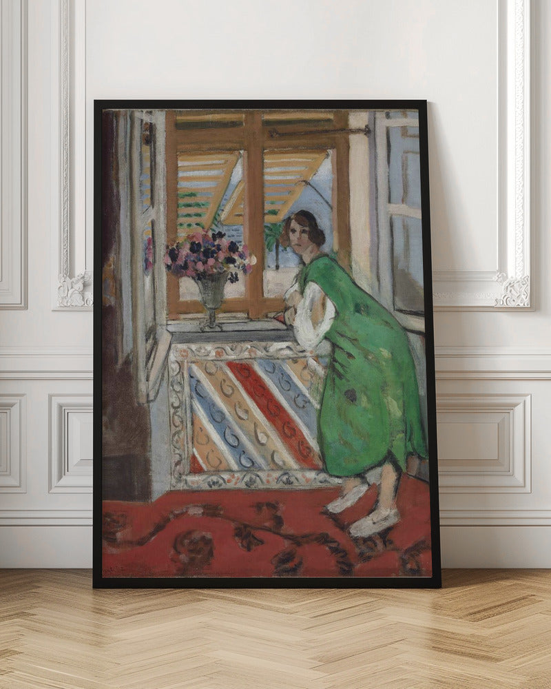 A painting by Henri Matisse depicting a woman in a loose green dress leaning on a windowsill and looking towards the viewer. Outside the open window with tan shutters, a sunny scene with a palm tree is visible. A vase of flowers sits on the sill above a colorful striped panel, and a red patterned rug covers the floor. Print