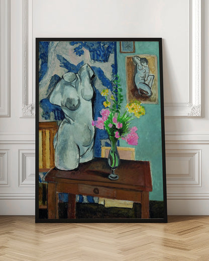 A colorful still life painting by Henri Matisse depicting a white plaster torso of a woman on a dark brown table next to a vase of bright pink and yellow flowers. The background features a blue and white patterned fabric and a light blue wall with a small framed nude drawing. Decor