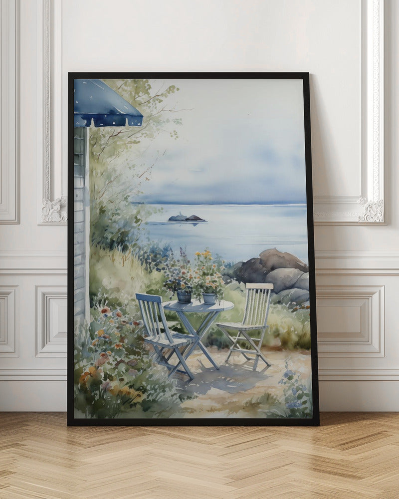 A watercolor painting of a tranquil coastal scene. A light blue bistro table and two matching chairs sit in a lush garden filled with flowers, overlooking a calm body of water. In the distance, a small island is visible under a soft, hazy sky. Part of a house with a blue awning can be seen on the left. Print