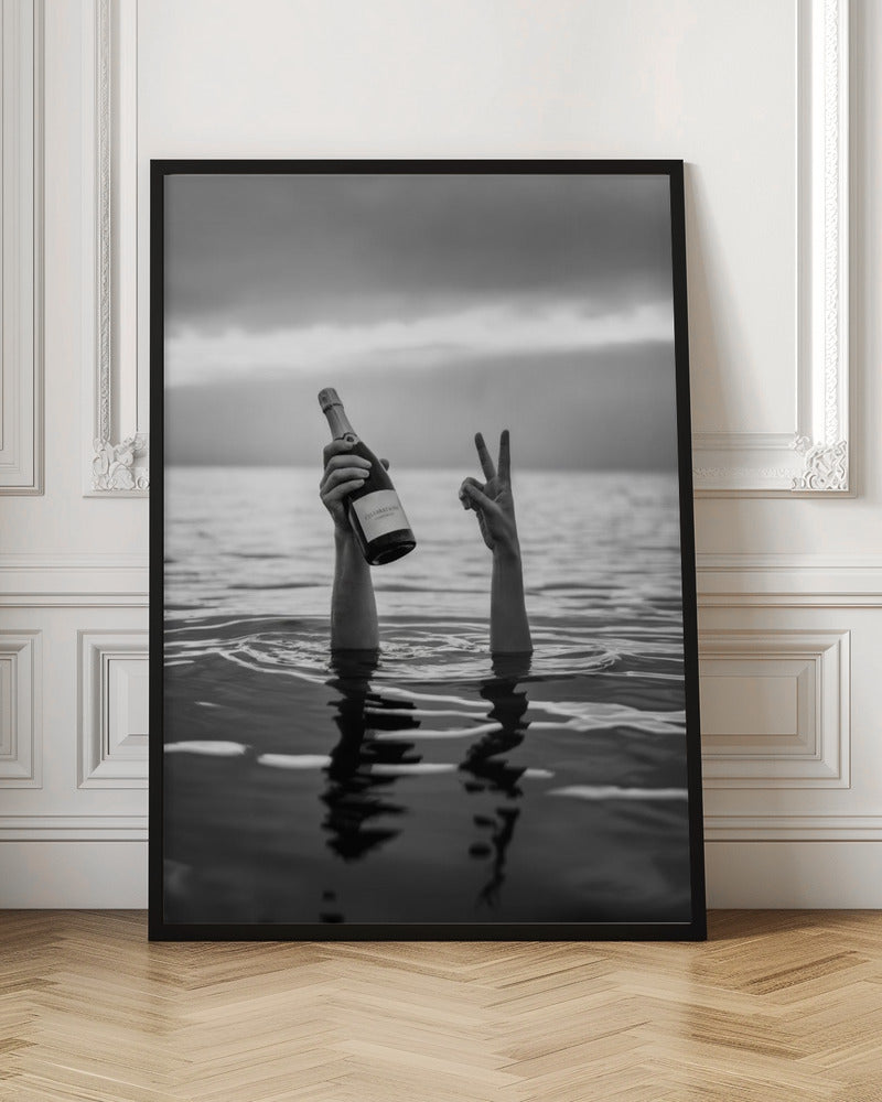 A black and white vertical photograph showing two arms sticking out of calm water. One hand holds a bottle of champagne, while the other makes a peace sign, all under a cloudy sky. Poster