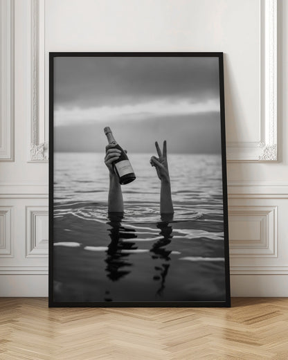 A black and white vertical photograph showing two arms sticking out of calm water. One hand holds a bottle of champagne, while the other makes a peace sign, all under a cloudy sky. Poster