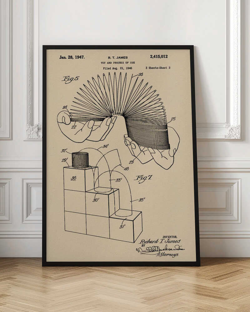 A framed vintage patent illustration for the Slinky toy on beige paper. The drawing, dated 1947, shows two diagrams: one with hands stretching the coiled spring toy, and another demonstrating the toy 'walking' down a set of blocks. Wall Art