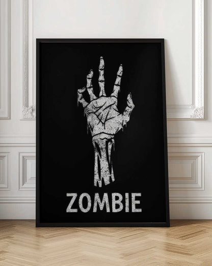 A black and white graphic of a distressed, skeletal zombie hand reaching up against a solid black background. Below the hand, the word 'ZOMBIE' is written in a bold, distressed font. The entire image is bordered by a thin black frame. Decor
