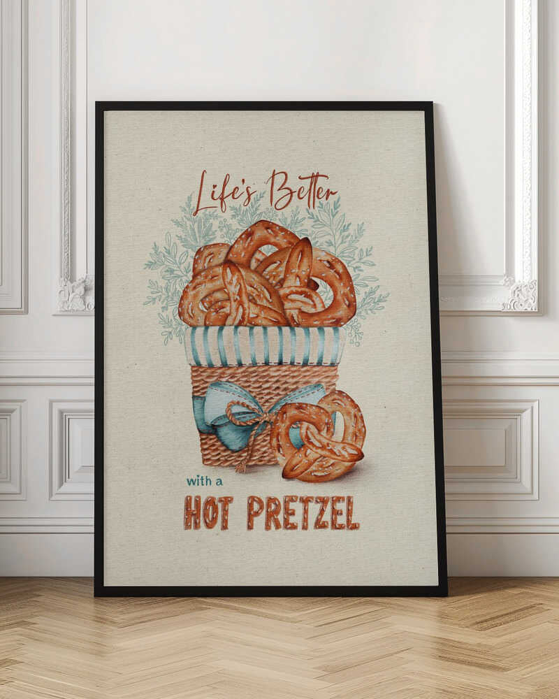 A vintage-style framed artwork featuring a watercolor illustration of a wicker basket overflowing with golden-brown pretzels. The text reads 'Life's Better with a HOT PRETZEL' in a warm brown font against a cream-colored textured background. A blue ribbon is tied around the basket, and light blue foliage is visible behind it. Poster