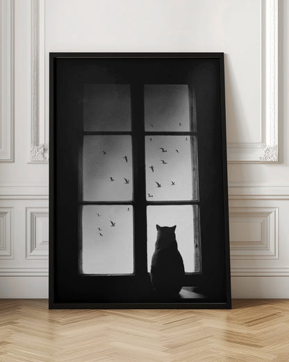 A black and white photograph showing the silhouette of a cat from behind, sitting on a windowsill and looking out through the panes at a flock of birds flying in the sky. Poster