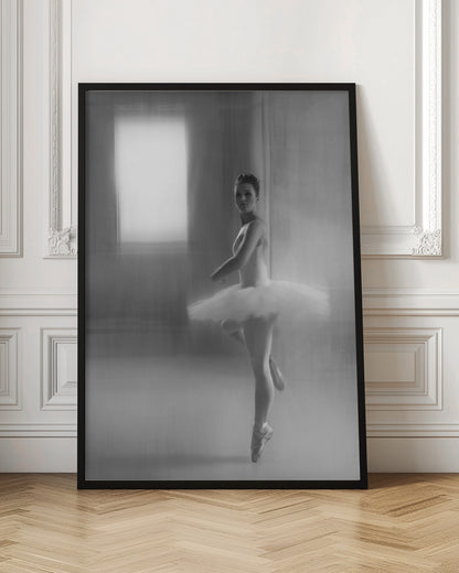 A black and white artistic photograph of a ballerina in a white leotard and tutu, mid-pose on pointe. The image has a motion blur effect, creating a dreamy and ethereal atmosphere as she glances back at the camera. Decor