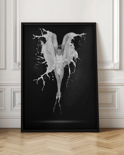 A dramatic black and white photograph of a ballerina suspended in mid-air against a black background. She is en pointe, and a dynamic splash of white liquid surrounds her, creating the illusion of wings. Artwork