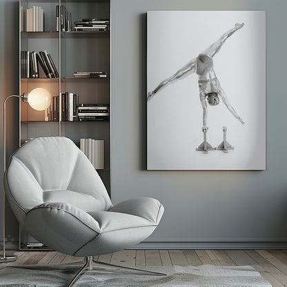 A black and white studio photograph of a muscular gymnast coated in silver paint, performing a dynamic one-armed handstand on a small block. Their legs are split wide apart in a display of strength and flexibility against a clean white background, all enclosed in a black frame. Decor