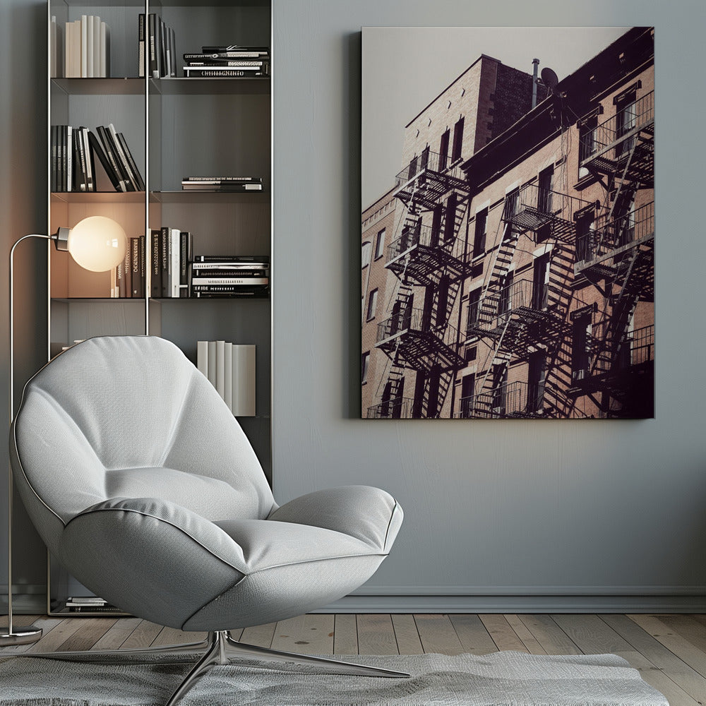 A low-angle photograph of a classic brick apartment building, with a complex pattern of black metal fire escapes casting long, dramatic shadows across the sunlit facade against a pale sky. Decor