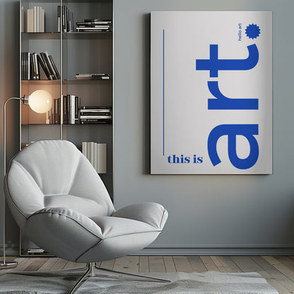 A minimalist art print in a black frame, featuring a white background with blue text. The word 'art' is written vertically in a large, bold lowercase font. To the left, smaller text reads 'this is'. At the top right, 'hello art' is written next to a blue starburst graphic. Wall Art