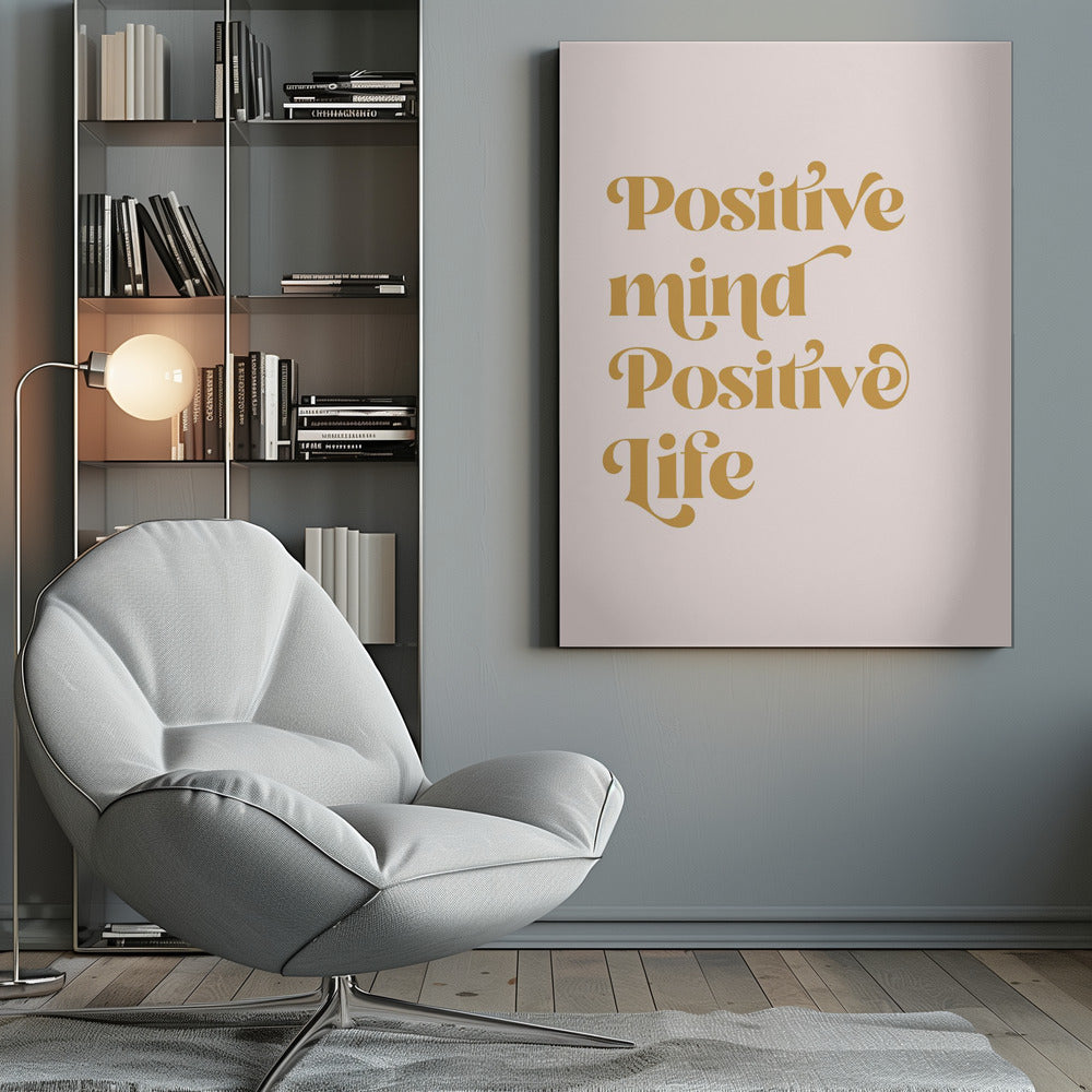 A framed art print featuring the motivational quote 'Positive mind Positive life' in a gold, retro-style font against a light pink background. The text is centered and arranged vertically. Artwork