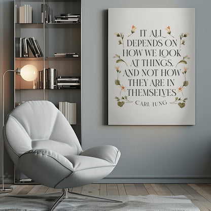 A framed art print featuring an inspirational quote by Carl Jung. The text reads 'It all depends on how we look at things, and not how they are in themselves' in a black serif font against an off-white background. The quote is encircled by a delicate wreath of watercolor botanicals with green leaves and pale orange flowers. Poster