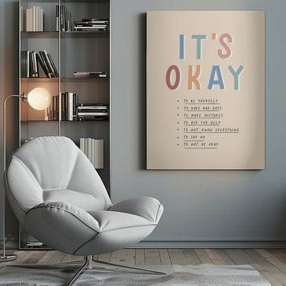 An inspirational framed poster with the words 'IT'S OKAY' in large, colorful letters. Below is a list of affirmations including 'TO BE YOURSELF', 'TO HAVE BAD DAYS', and 'TO MAKE MISTAKES' on a beige background. Artwork