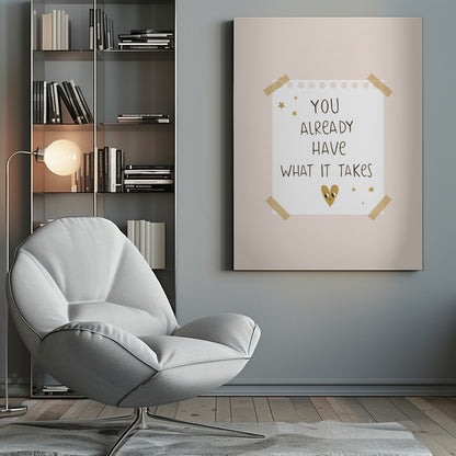 A motivational poster in a black frame with a pale pink background. A white piece of notebook paper is taped to the center with the handwritten text 'YOU ALREADY HAVE WHAT IT TAKES' in brown. It's decorated with small gold stars and a cute, smiling gold heart. Decor