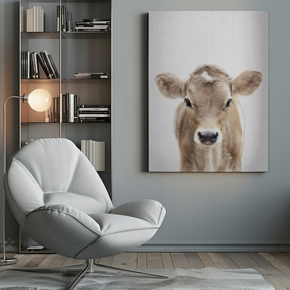 A close-up portrait of a light brown baby cow looking directly at the camera against a stark white background, enclosed in a simple black frame. Artwork