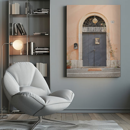 A charming European bookstore entrance featuring a large, dark grey arched door set against a peach-colored wall. Above the door, a sign reads 'LIBRERIA' below a decorative fanlight window and a hanging lantern. Decor