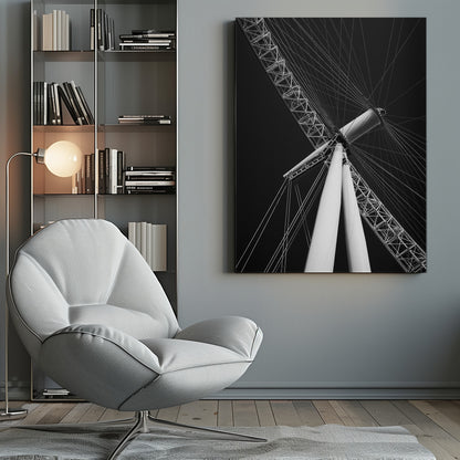 A dramatic low-angle, black and white photograph of a large Ferris wheel, focusing on the central hub and supporting structure. The image captures the white A-frame legs and the intricate lattice of the wheel's rim, with numerous tension cables radiating outwards against a solid black sky, creating a strong sense of perspective and geometric pattern. Artwork
