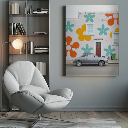 A retro-style gray convertible parked on a city street in front of a building with a large, colorful pop-art mural of stylized flowers in orange, yellow, and turquoise. Decor