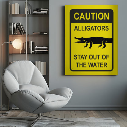 A yellow and black rectangular warning sign in a black frame. The sign reads 'CAUTION ALLIGATORS' at the top, features a black silhouette of an alligator in the center, and says 'STAY OUT OF THE WATER' at the bottom. Decor