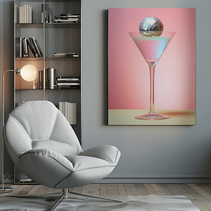 A sleek martini glass filled with an iridescent pink and blue cocktail is centered against a solid pink background. A small, shiny silver disco ball rests on the rim of the glass, completing the festive and stylish composition. Decor