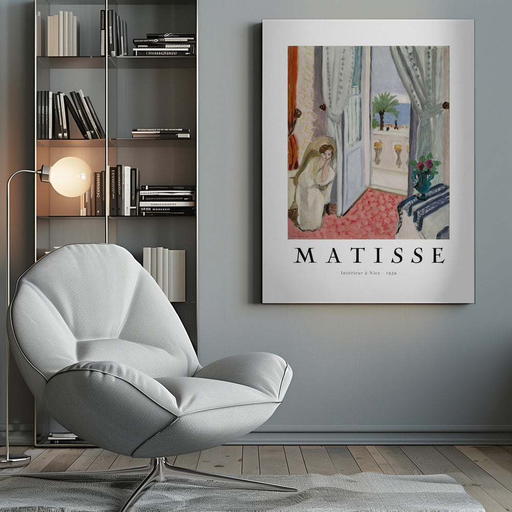 A framed art print of Henri Matisse's painting 'Intérieur à Nice - 1939'. The painting depicts a woman in a white robe sitting in a sunlit room with an open door leading to a balcony overlooking the sea and a palm tree. The poster has a white border with the artist's name and the title below the artwork. Artwork
