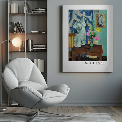 A framed art print of Henri Matisse's painting 'Le Torse en Plâtre'. The still life features a white plaster female torso sculpture next to a dark brown wooden table with a vase of pink and yellow flowers. The background consists of a blue and white patterned tapestry and a teal wall with a small framed nude drawing. Print