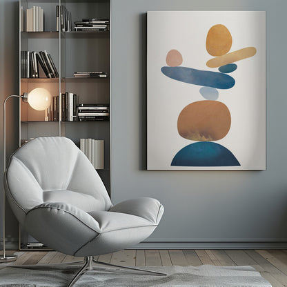An abstract art print in a thin black frame featuring a stack of colorful, organic shapes resembling balanced stones against a white background. The forms are in various shades of blue, earthy brown, ochre, and a muted pink, creating a sense of calm and equilibrium. Artwork
