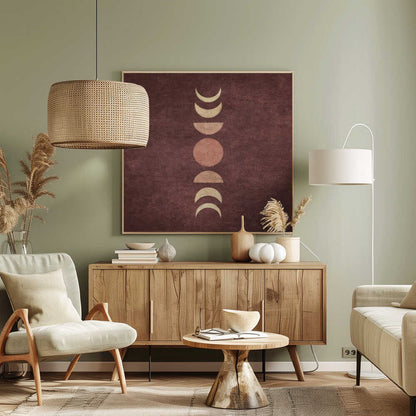 A minimalist piece of framed art showing the phases of the moon arranged vertically against a textured, deep maroon background. The moon shapes are colored in shades of cream and dusty rose, with the full moon in the center. Print
