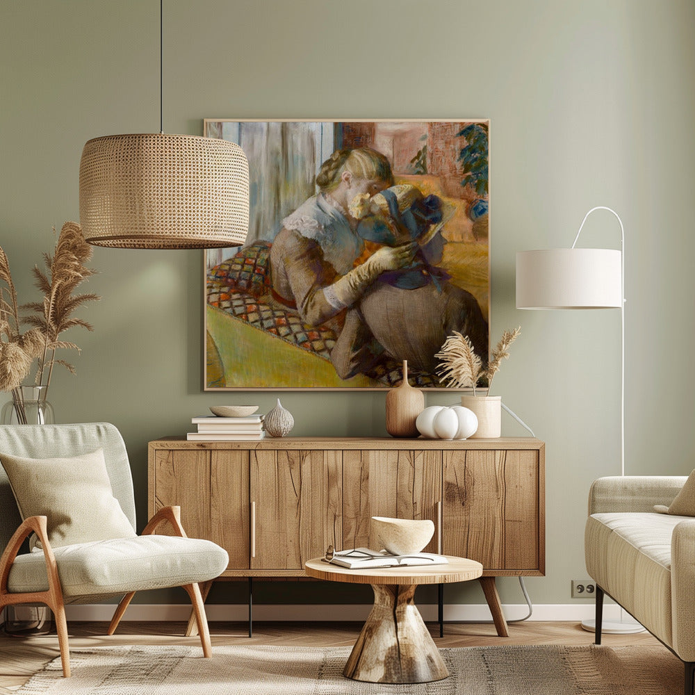 A framed Impressionist painting by Edgar Degas depicting two women. One woman, with blonde hair tied back, adjusts a hat with a blue ribbon on the other woman who is sitting with her back mostly to the viewer on a colorful patterned sofa. Print