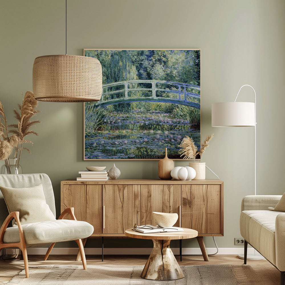 An Impressionist painting by Claude Monet, 'The Water Lily Pond', in a light wood frame. A pale green Japanese footbridge arches over a tranquil pond filled with pink and white water lilies, reflecting the lush green and blue foliage of weeping willows that surround it. Poster