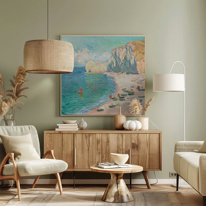 An impressionist painting by Claude Monet depicting the beach at Étretat, France, enclosed in a light wood frame. The artwork shows tall, light-colored cliffs on the right, a sandy beach with small boats, and vibrant turquoise water with a few red-sailed boats. The sky is partly cloudy. Decor