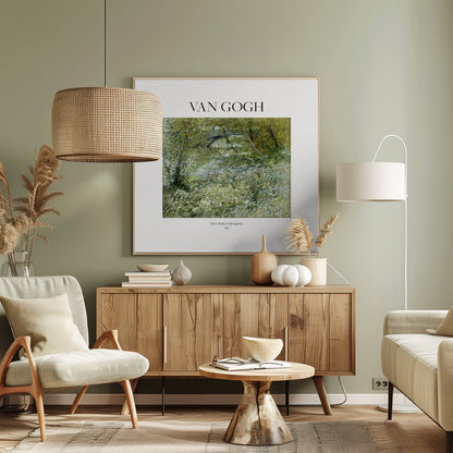 A framed art print of Vincent van Gogh's painting 'River Bank in Springtime'. The impressionist artwork depicts a lush green riverside scene with white flowers and a distant bridge, framed in light wood with a white mat. Wall Art